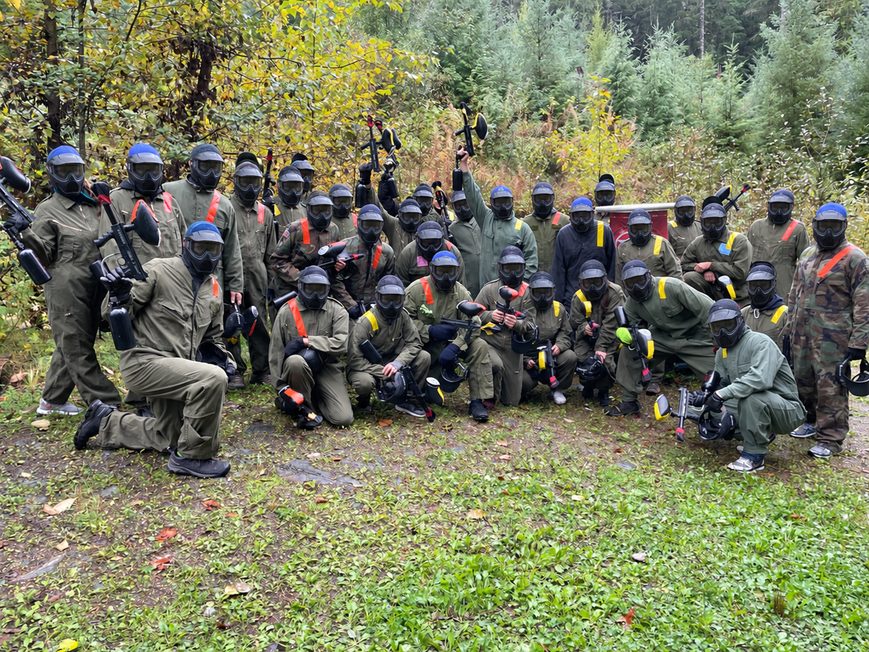 Corporate team gathered outdoors for a paintball retreat activity