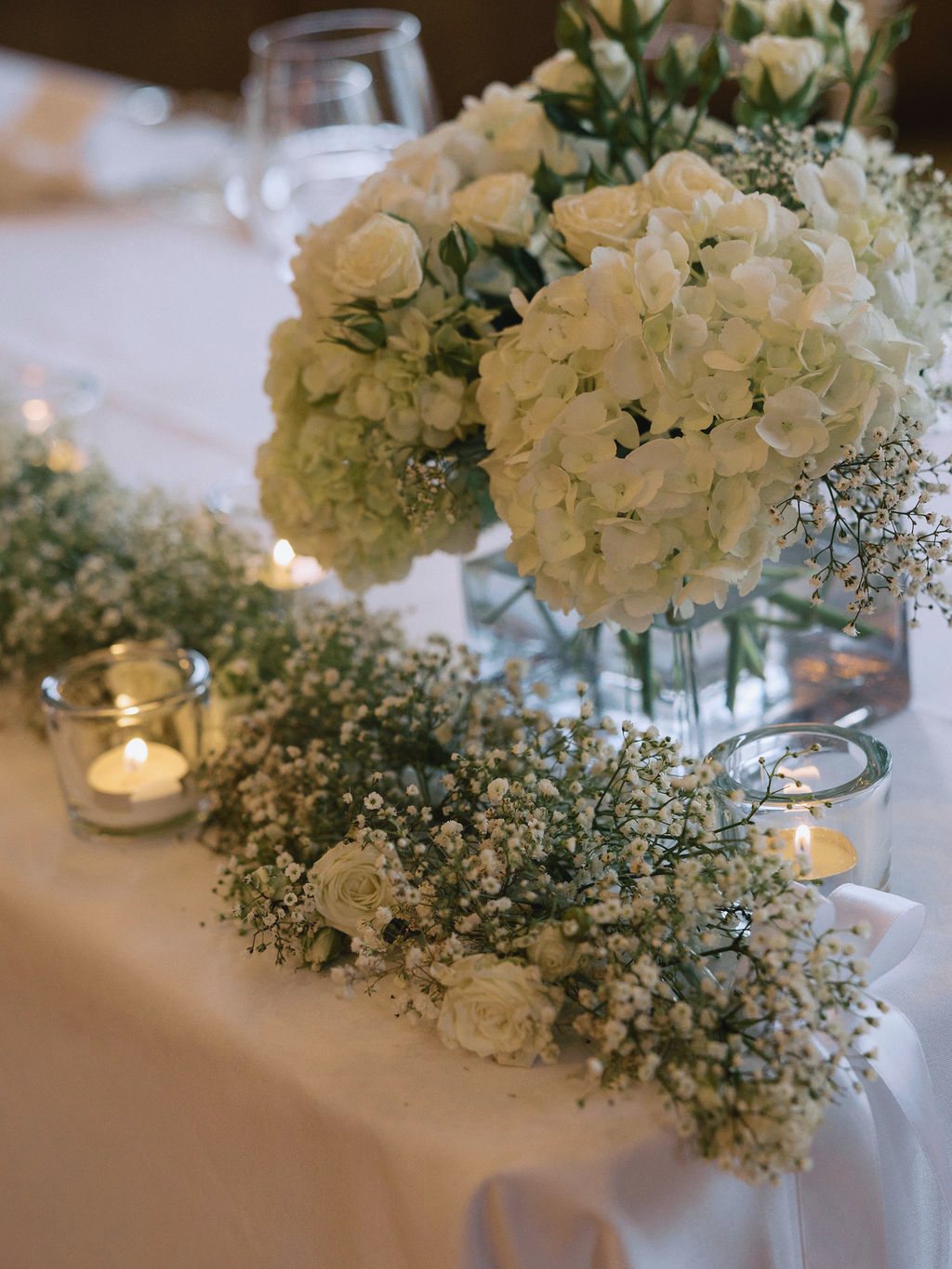 White hydrangeas, roses and candlelight at an elegant gathering