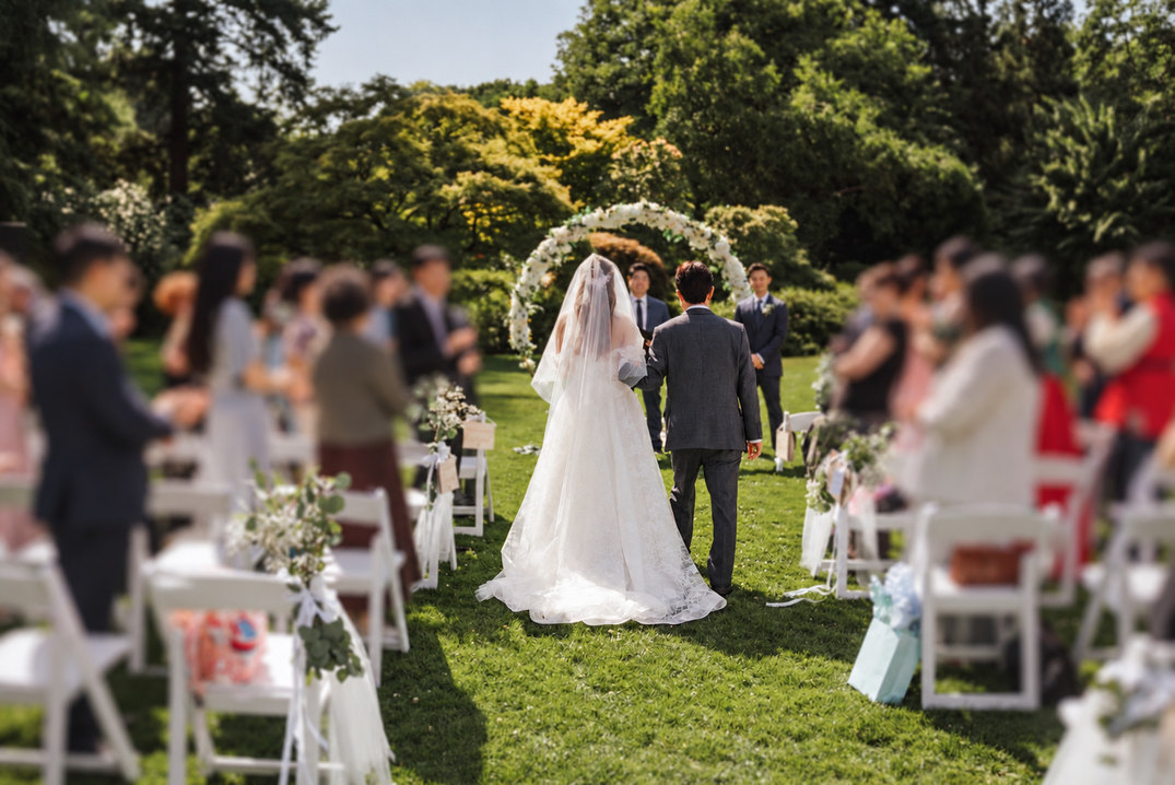 A couple walking through an outdoor wedding ceremony with their guests