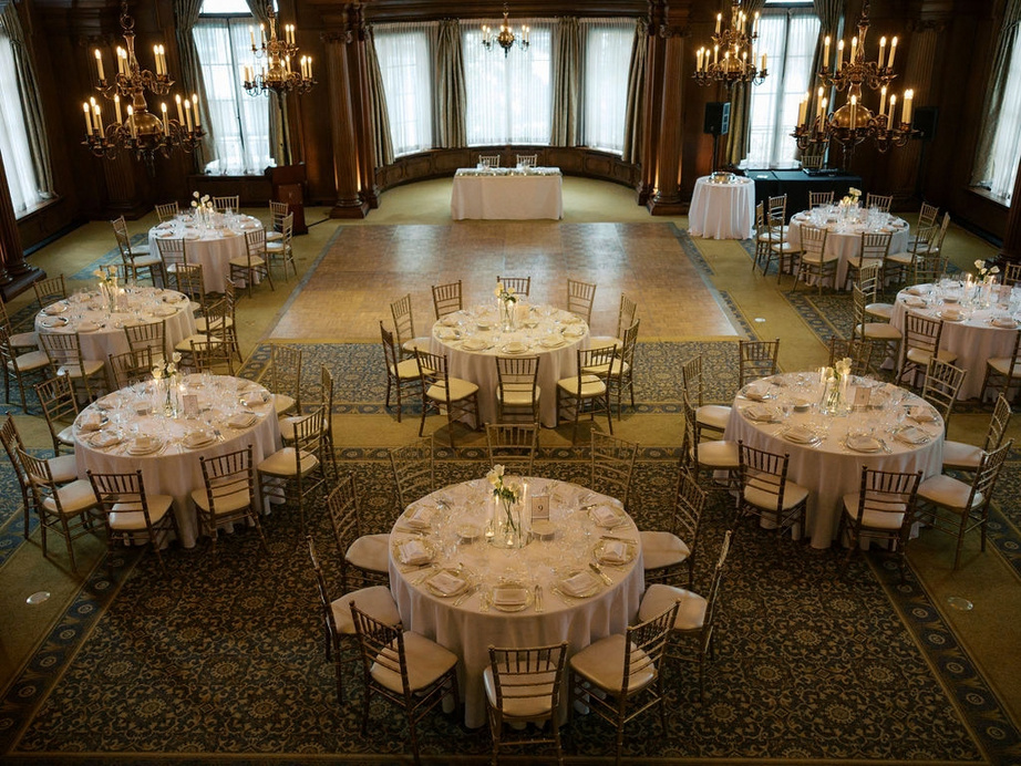 A wedding reception room set with round tables and candlelight